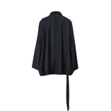 Back view of the BAQA black blazer showing the relaxed oversized fit and the long fabric belt detail.