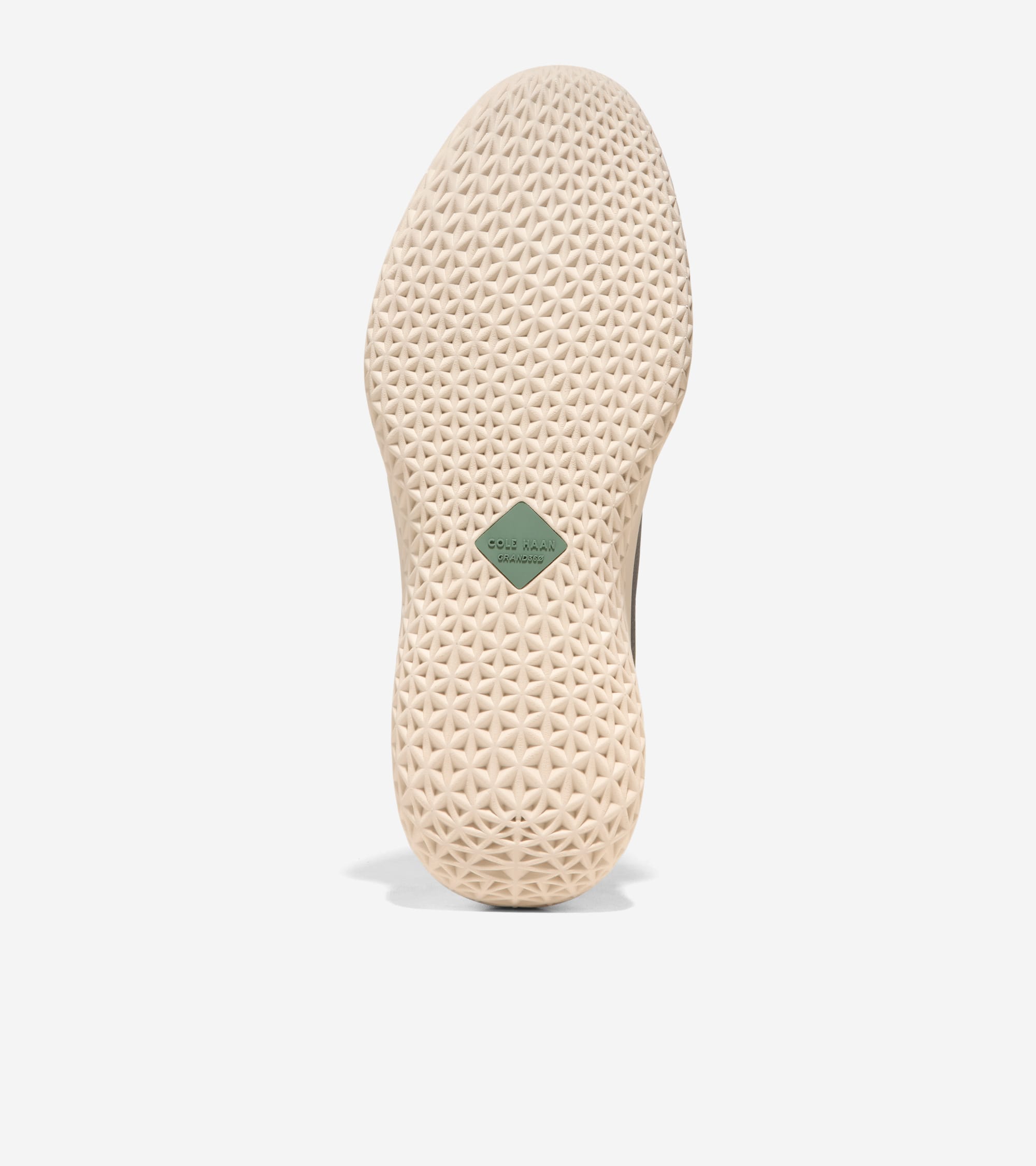 Light beige sneaker sole with a textured geometric pattern and a green diamond-shaped Cole Haan logo patch in the arch.
