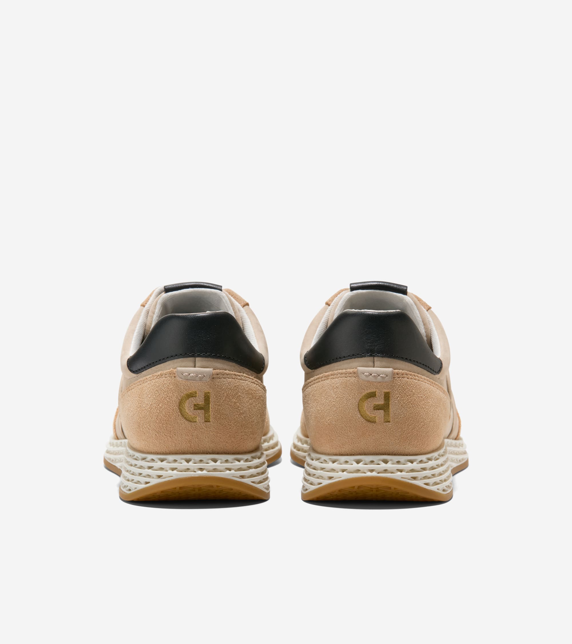 Tan suede sneakers, back view. Each has a black heel collar, gold-toned 'CH' logo, textured white midsole, and brown outsole.