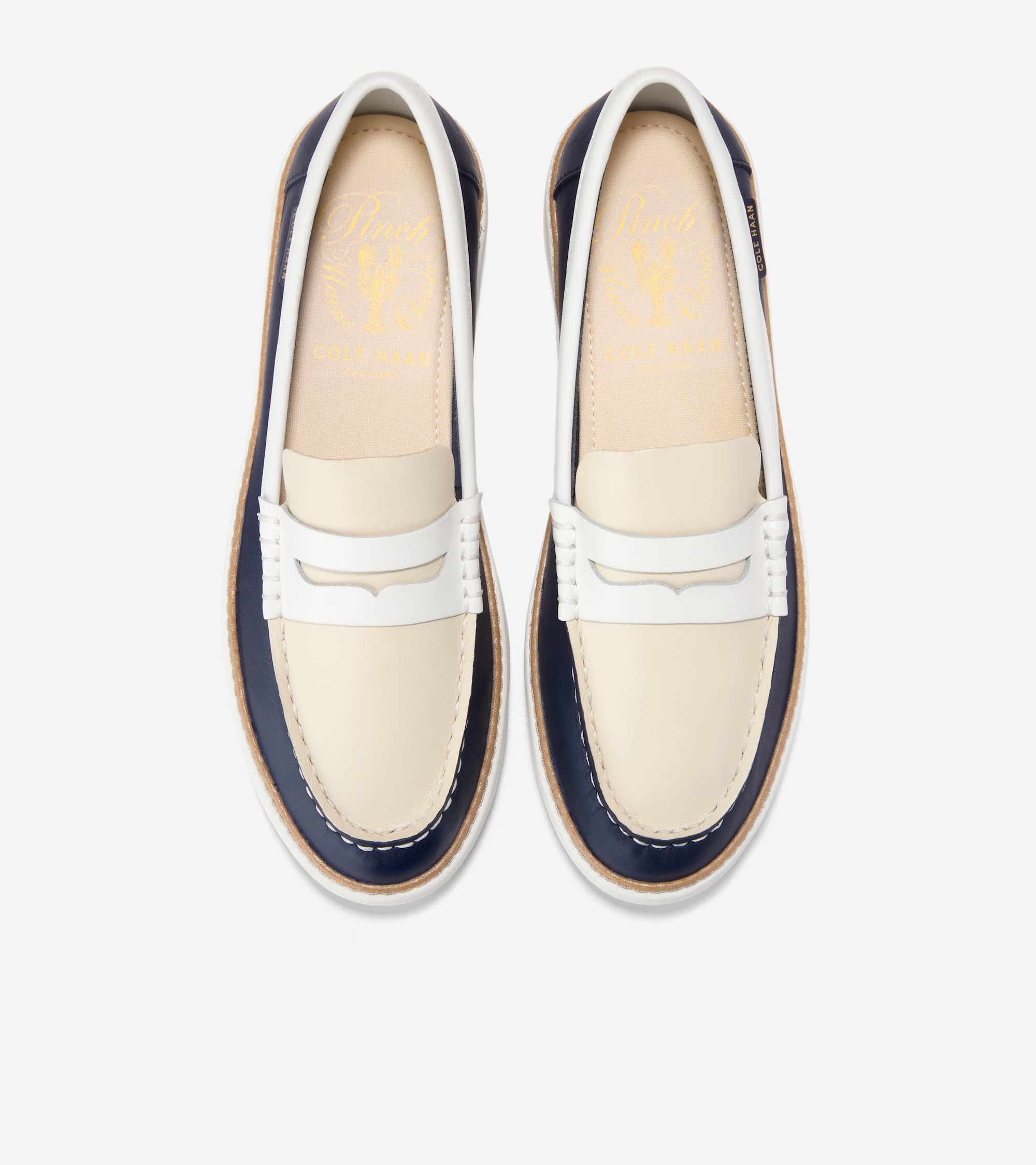 Pair of off-white and navy leather penny loafers with white penny straps, espadrille-style jute trim, and gold-toned interior