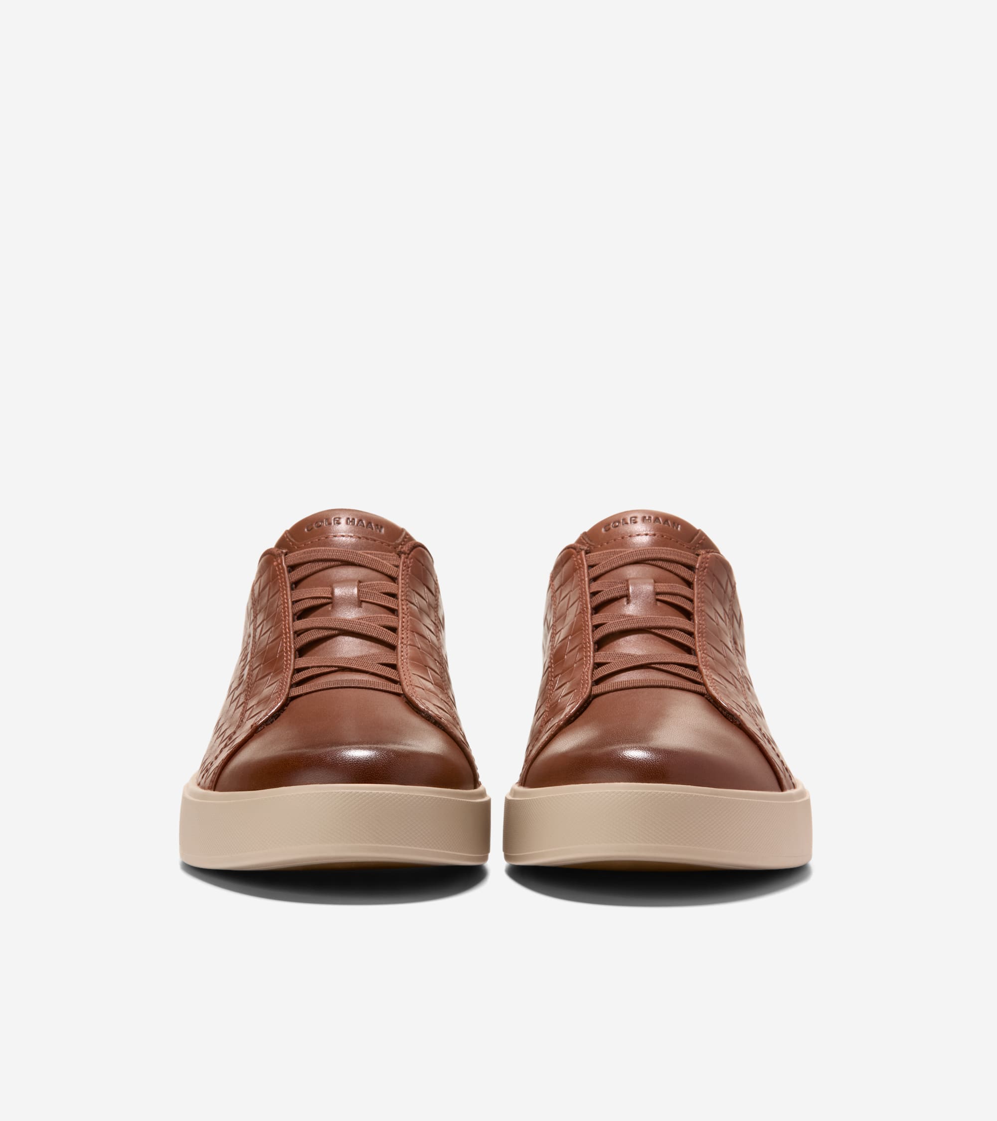 Pair of brown leather slip-on sneakers with woven side panels, smooth toe caps, elasticized laces, and thick light beige sole