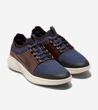Pair of navy knit sneakers with brown perforated side panels, navy laces, a ribbed collar, and a cream sole with black toe tr