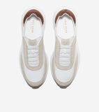 White slip-on sneakers with beige suede overlays, white elastic laces, and a brown heel collar lining. Features a chunky whit