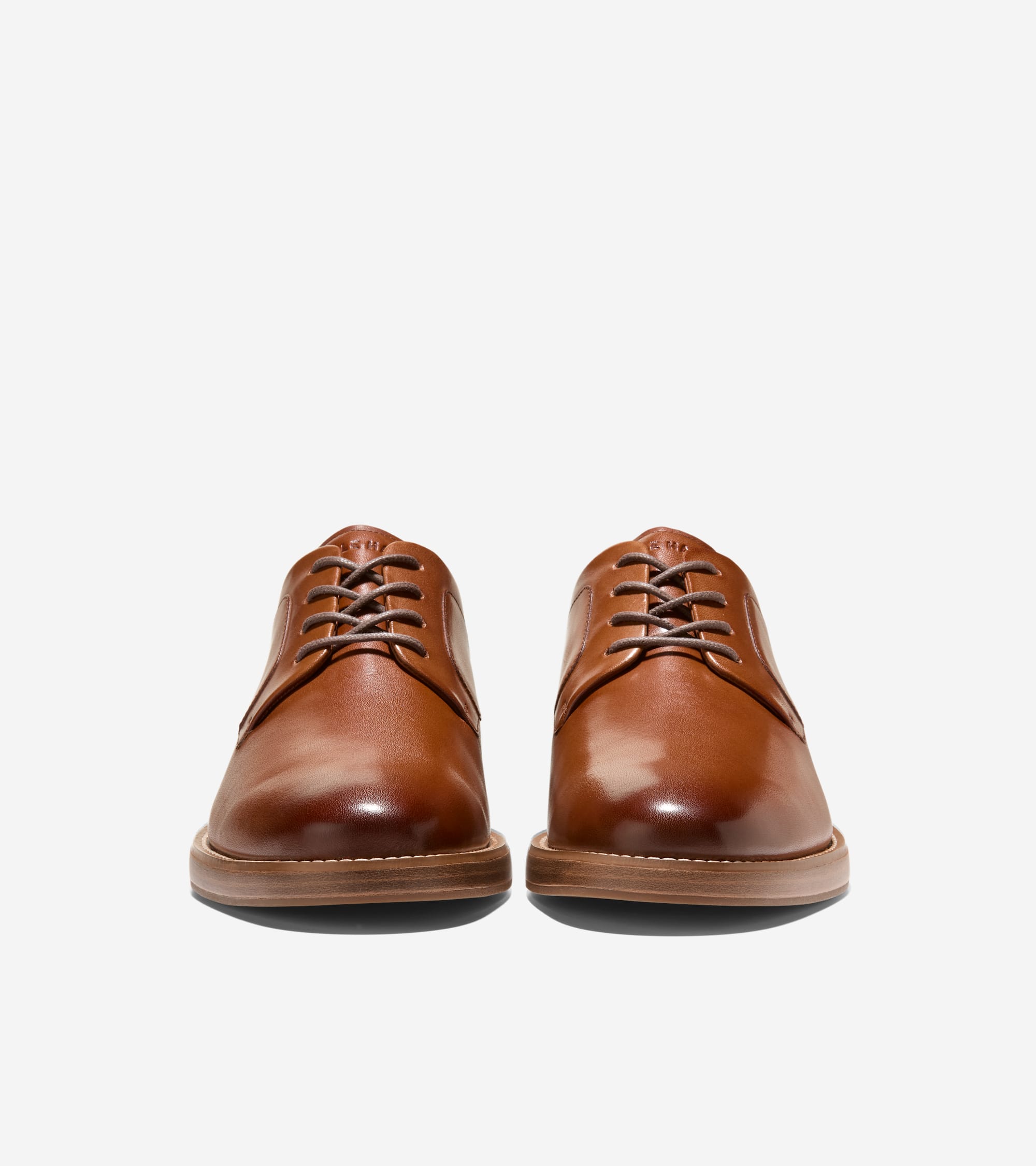 Pair of tan leather plain toe oxfords with brown laces and a light brown stitched sole.