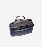 Navy blue slim briefcase with brown handles, silver-toned zippers, and dark grey trim. Main compartment open, revealing grey