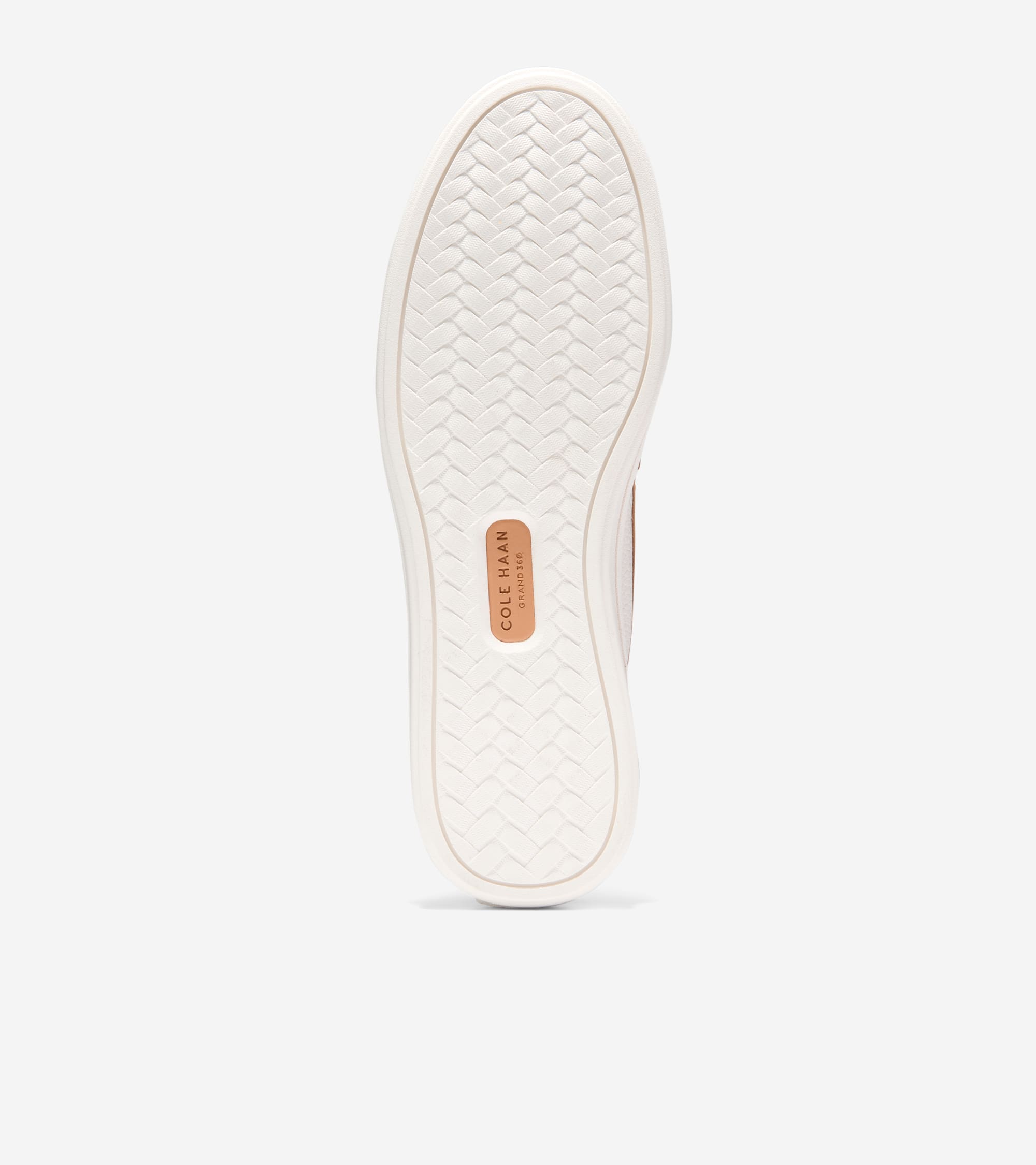 Off-white loafer sole with woven texture and a brown Cole Haan logo patch. Light brown upper visible.