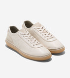 Cream pebbled leather low-top sneakers with matching laces, suede-like side panels, and translucent tan rubber soles.
