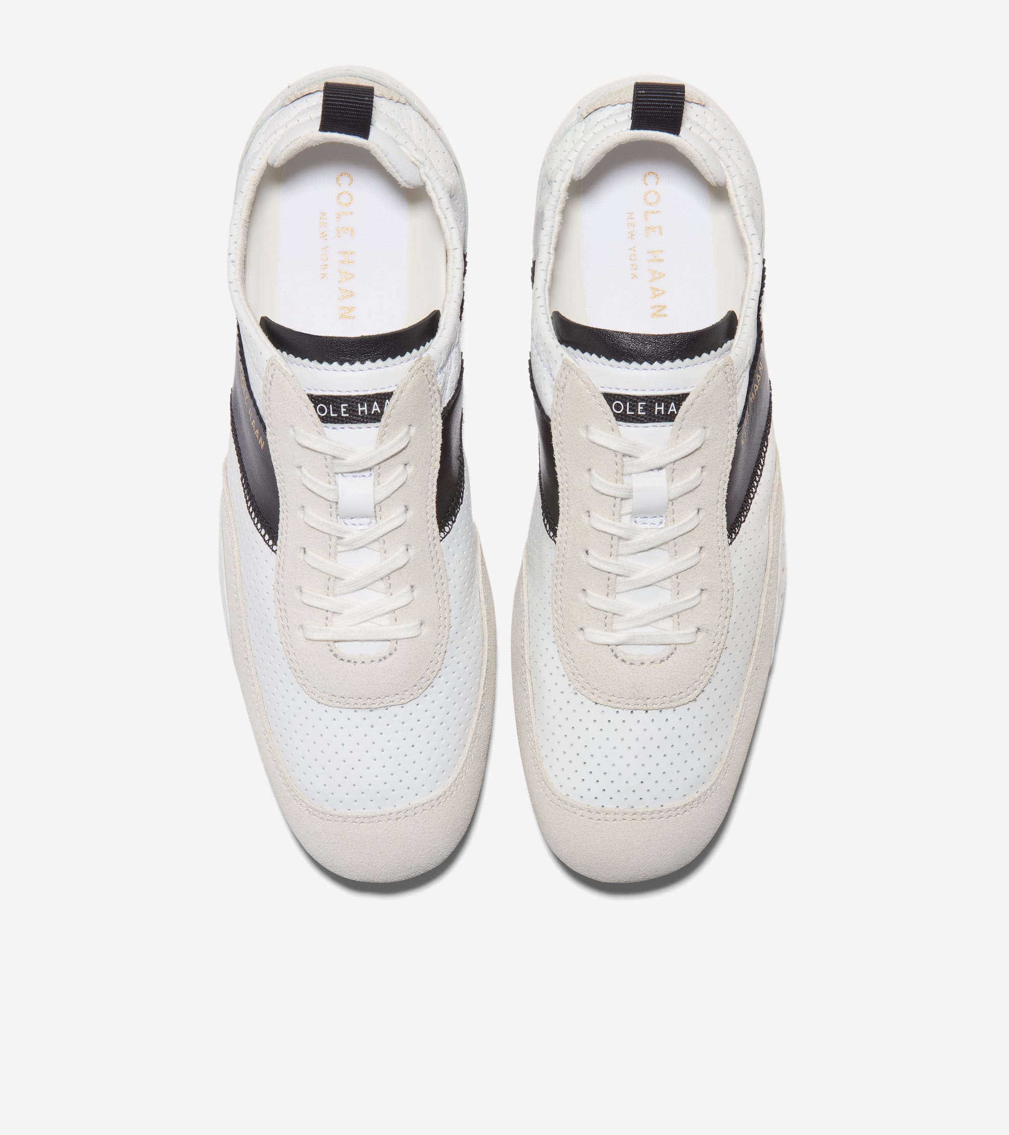 Pair of white perforated sneakers with off-white suede overlays, black side stripes, and white laces. Black heel tabs.