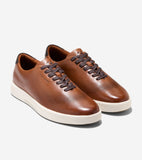 Brown leather sneakers with perforated toe and sides, brown laces, white soles, and dark brown collar trim.