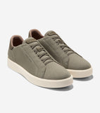 Pair of olive green knit slip-on sneakers with fixed laces, a tan inner collar, and thick off-white soles.