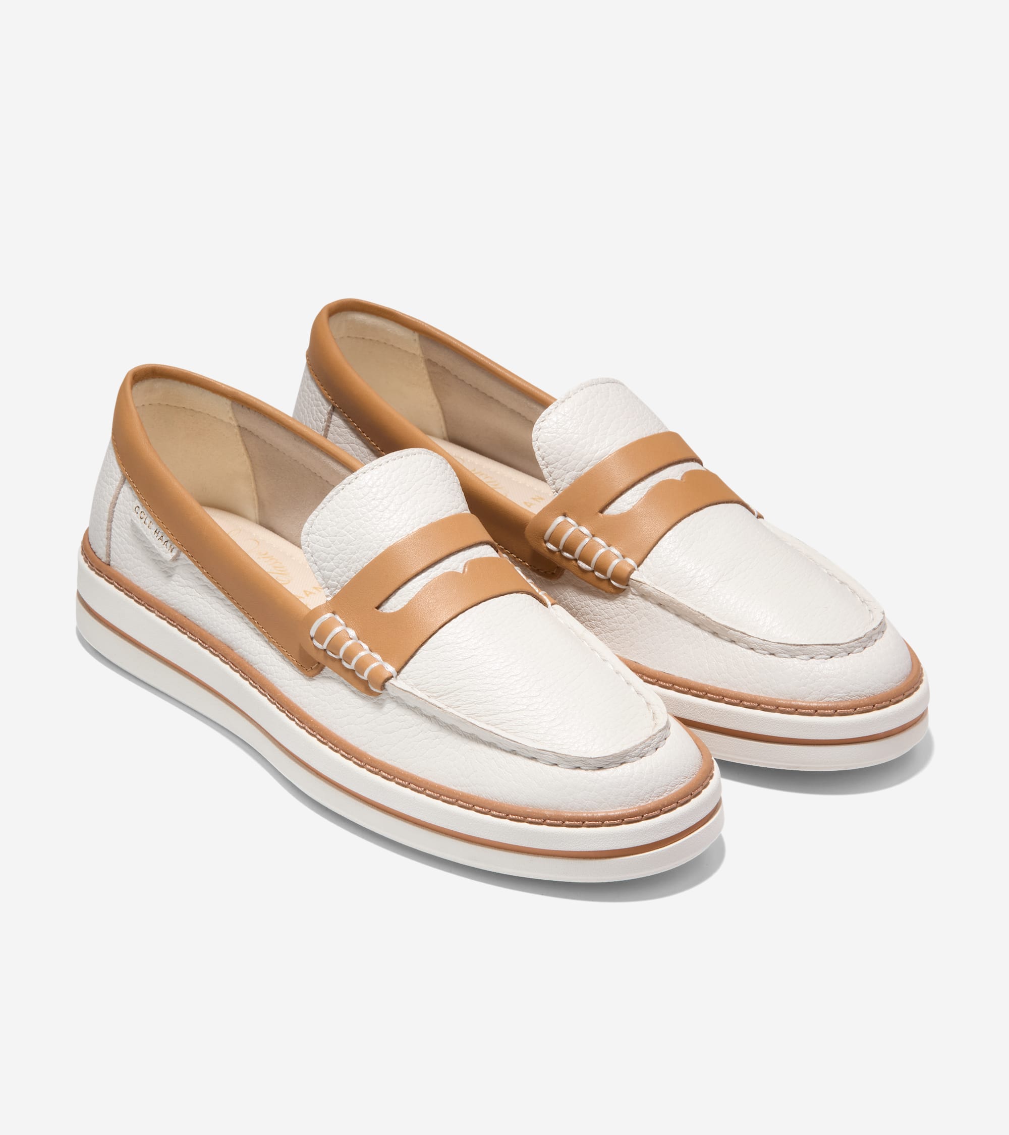 Pair of white textured leather penny loafers with tan penny straps, tan piping, and a white platform sole with a tan stripe.