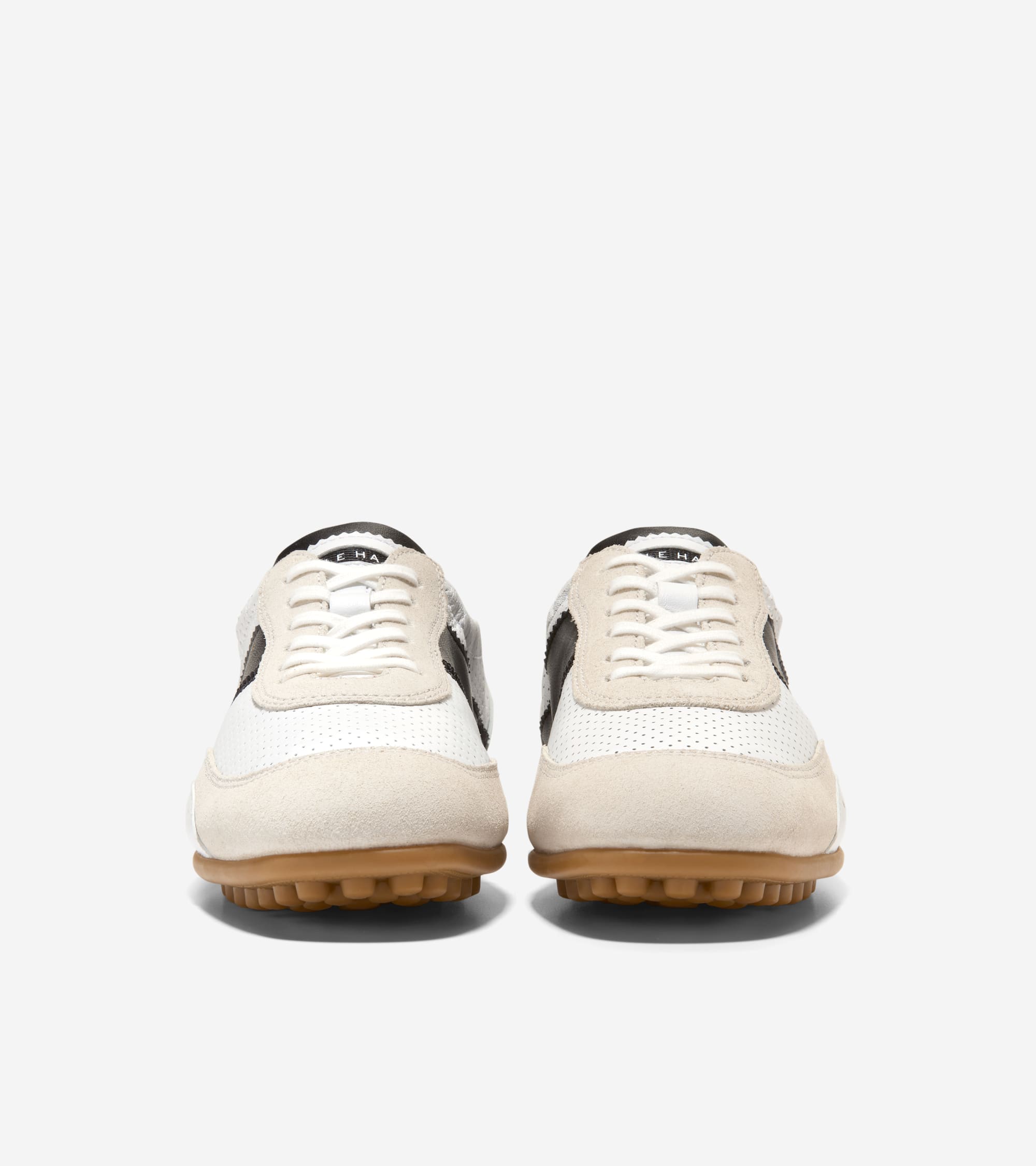 White perforated and off-white suede sneakers with black side stripes, white laces, and brown lugged rubber soles.