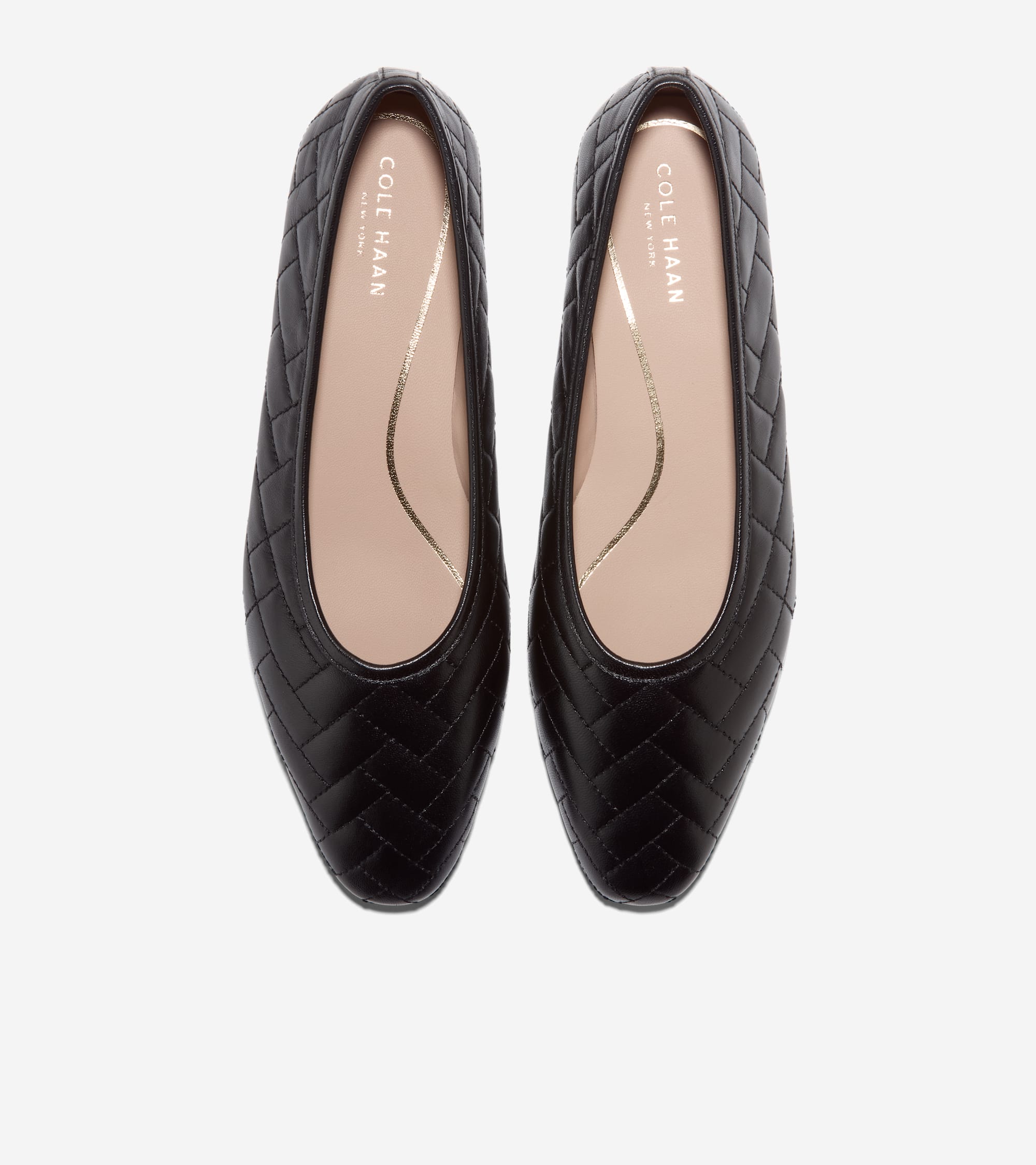 Pair of black quilted ballet flats with pointed toes. They have light tan insoles with gold-toned brand text and a wavy line.