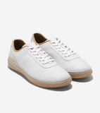 White leather low-top sneakers with white laces, light tan collar lining, beige suede heel panel, and light tan rubber soles.