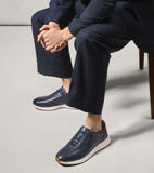 Men's navy leather slip-on sneakers with elastic laces, white midsoles, brown outsoles, and Cole Haan branding.