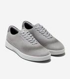 Pair of light grey leather sneakers with laser-cut perforations, grey laces, darker grey heel collar, Cole Haan branding, and