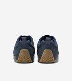 Dark blue suede sneakers with tan rubber soles featuring a diamond-grid pattern and 'COLE HAAN' text embossed on the heel.