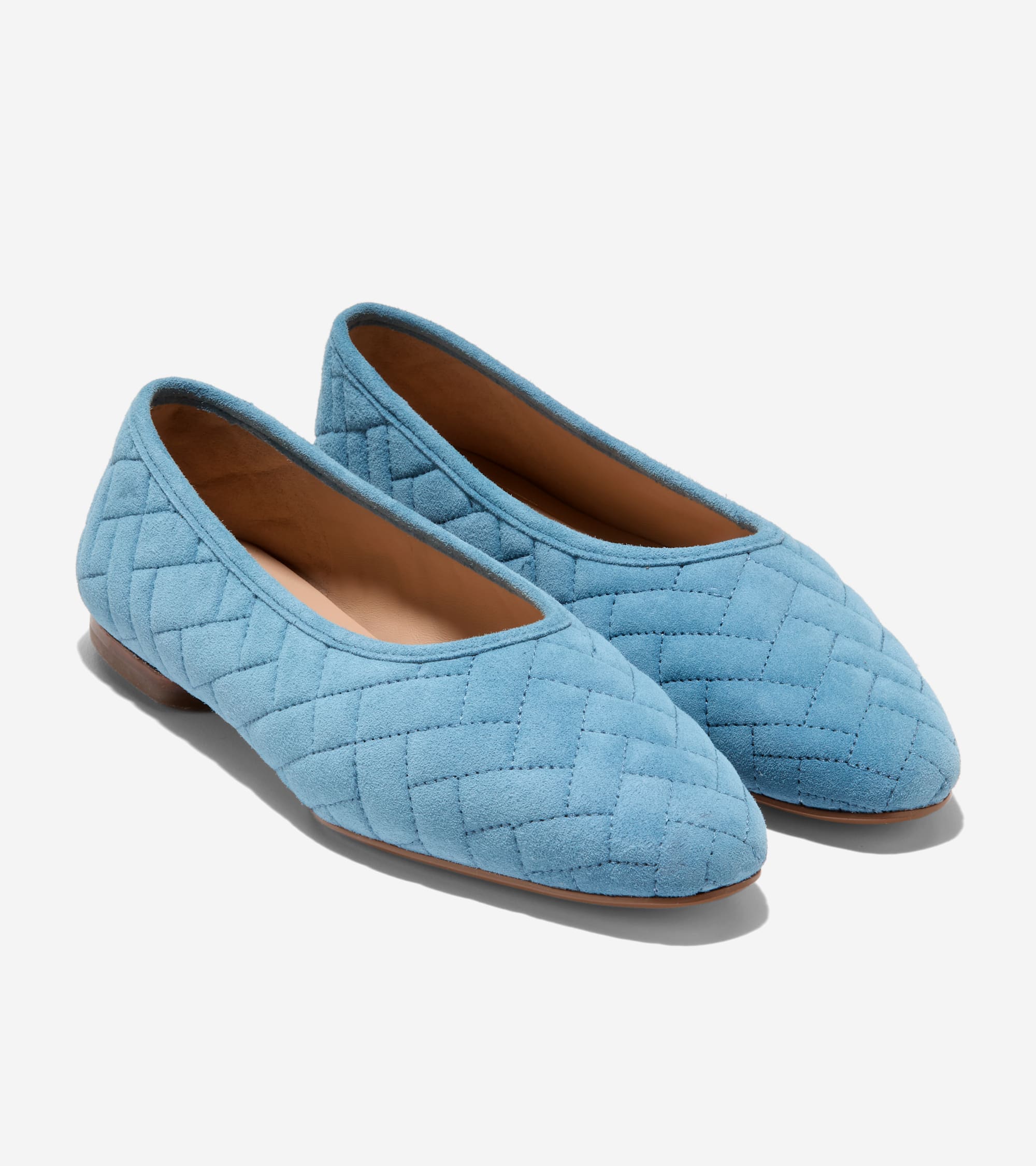 Pair of light blue suede-like quilted ballet flats with rounded toes and low brown soles.