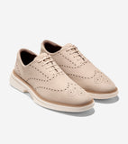 Light beige pebbled leather wingtip oxfords with brogue perforations, matching laces, and a thick cream sole with a tan welt.