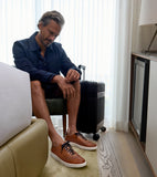 Brown leather low-top sneakers with laser-perforated uppers, dark laces, and thick white soles.