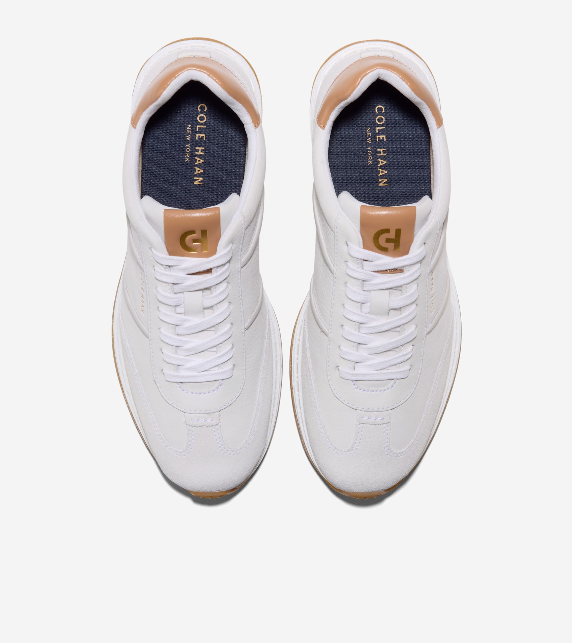 White sneakers with white laces, tan collar lining, dark blue insoles with white text, gold-toned CH logo, and gum outsoles.