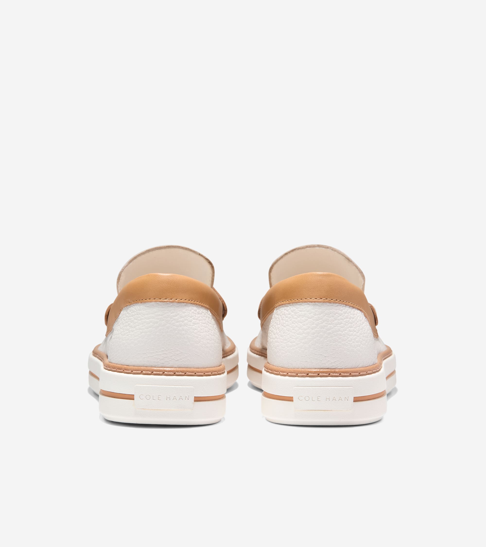 Pair of white pebbled leather loafers with tan leather trim, white platform soles, and tan accent stripes. Cole Haan logo on
