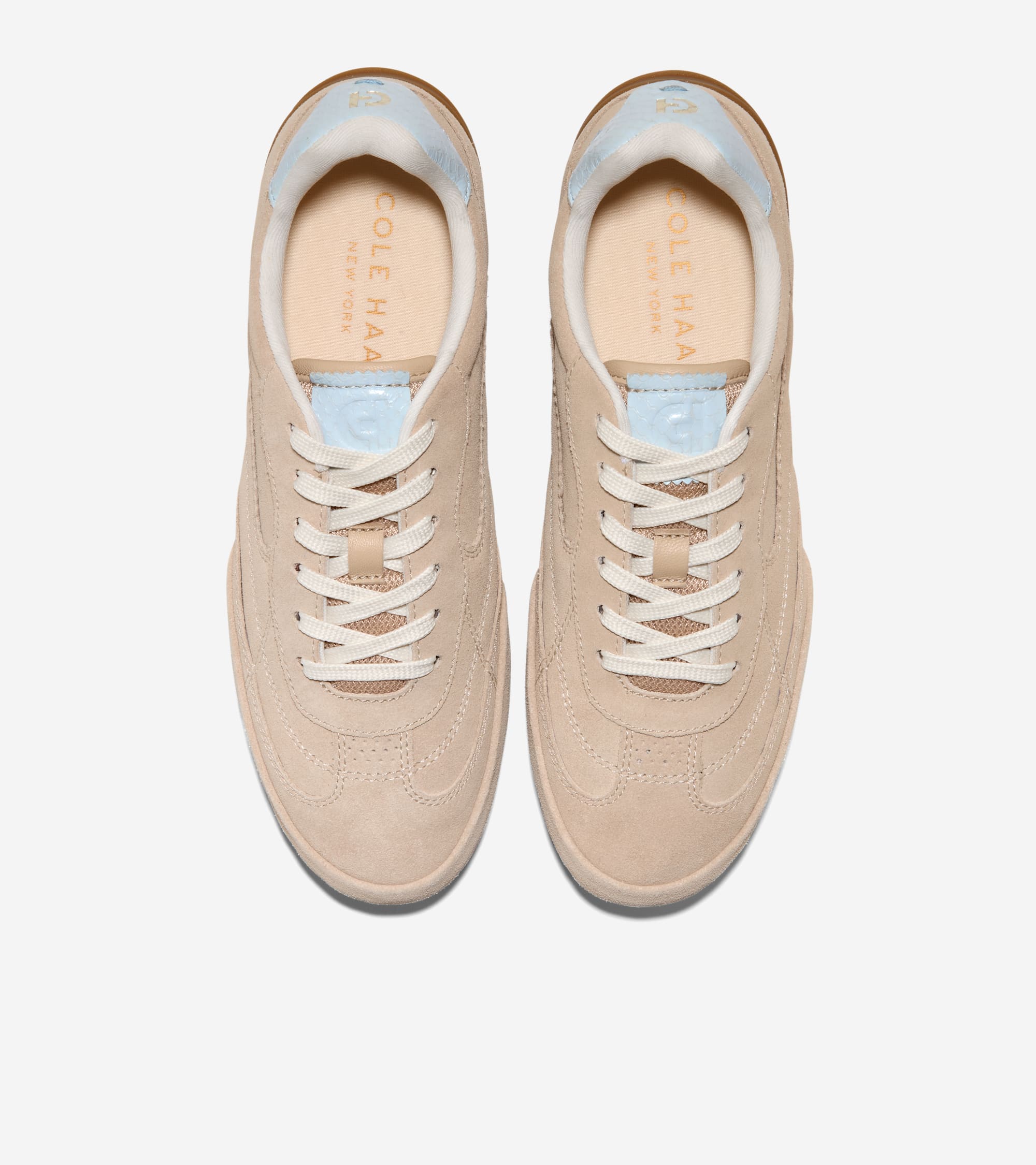 Light beige suede sneakers with white laces, mesh tongue, light blue trim on the heel collar, and light beige soles.