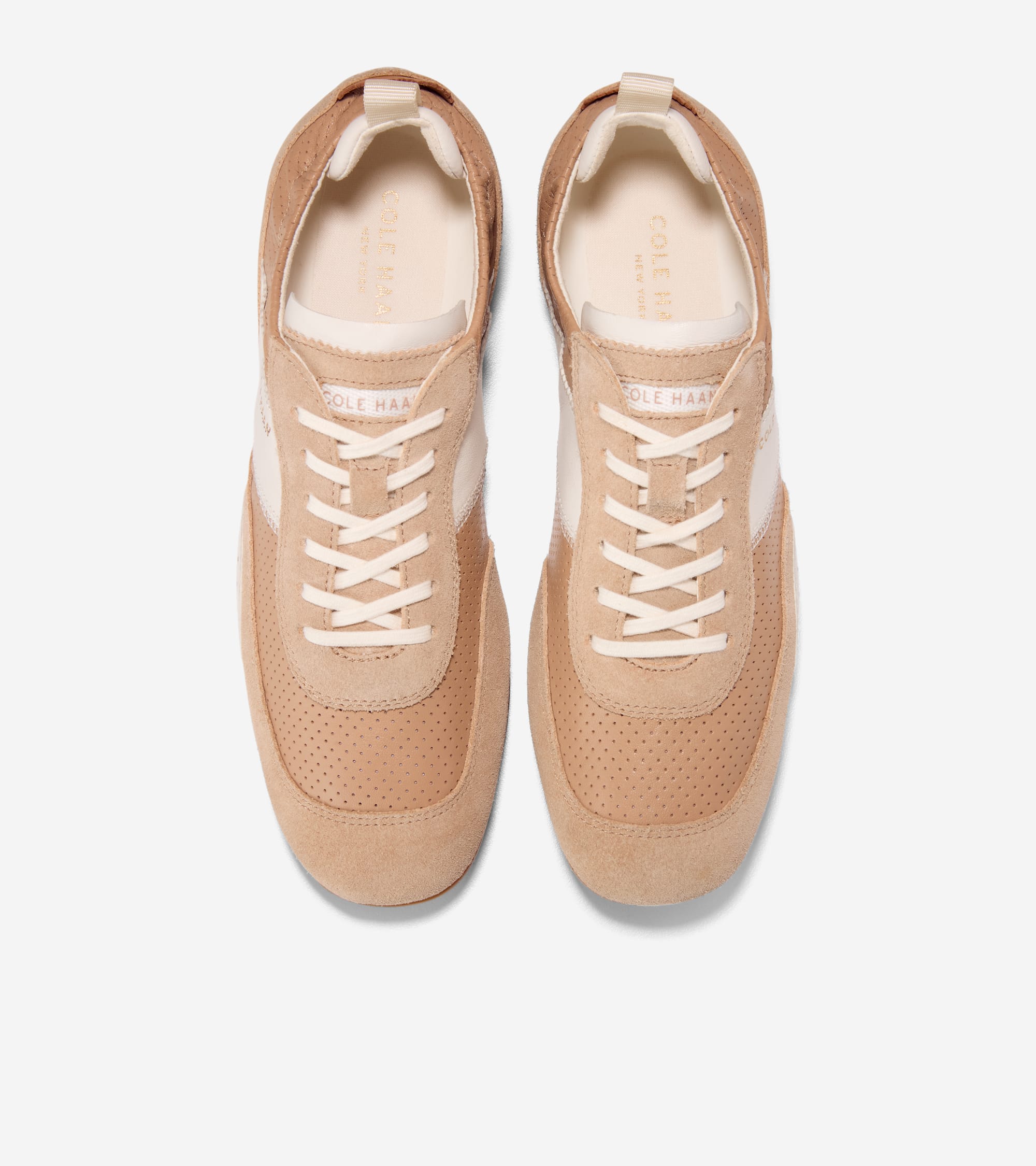 Pair of light tan suede sneakers with perforated toe boxes, off-white side stripes, laces, and collar lining.