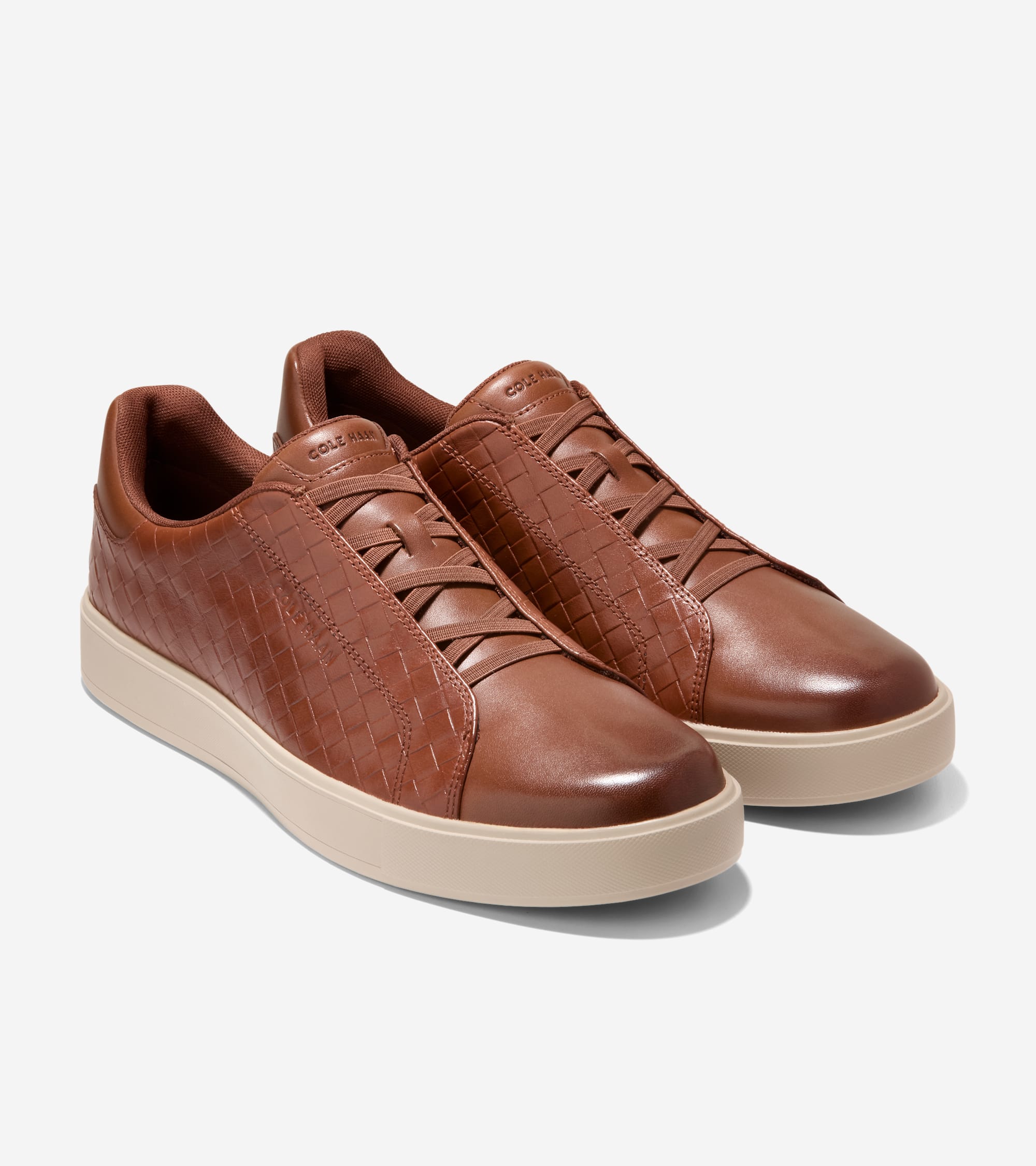 Pair of brown leather slip-on sneakers with woven sides, smooth toe, elastic laces, and tan soles.