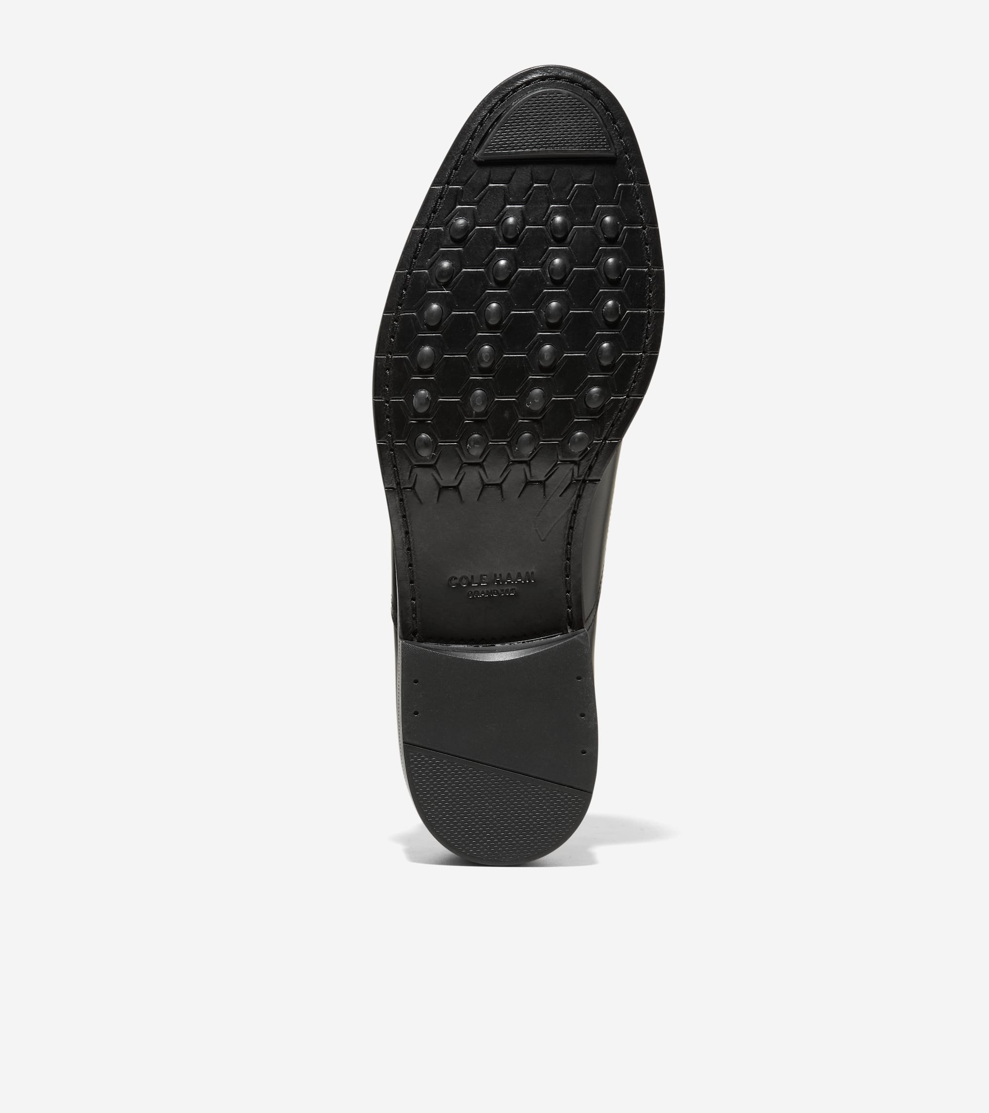 Black oxford shoe sole featuring a hexagonal pattern of nubs and a textured heel. Cole Haan branding is visible.