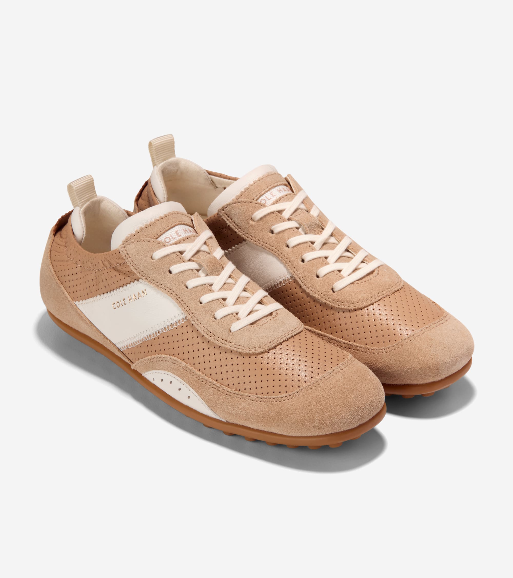 Pair of tan leather and suede sneakers with perforated sides, off-white laces, side stripe with "COLE HAAN" text, and brown s