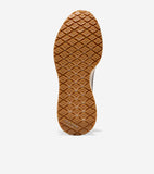 Brown sneaker sole with diamond-patterned tread and Cole Haan Grand.ØS logo at the heel.