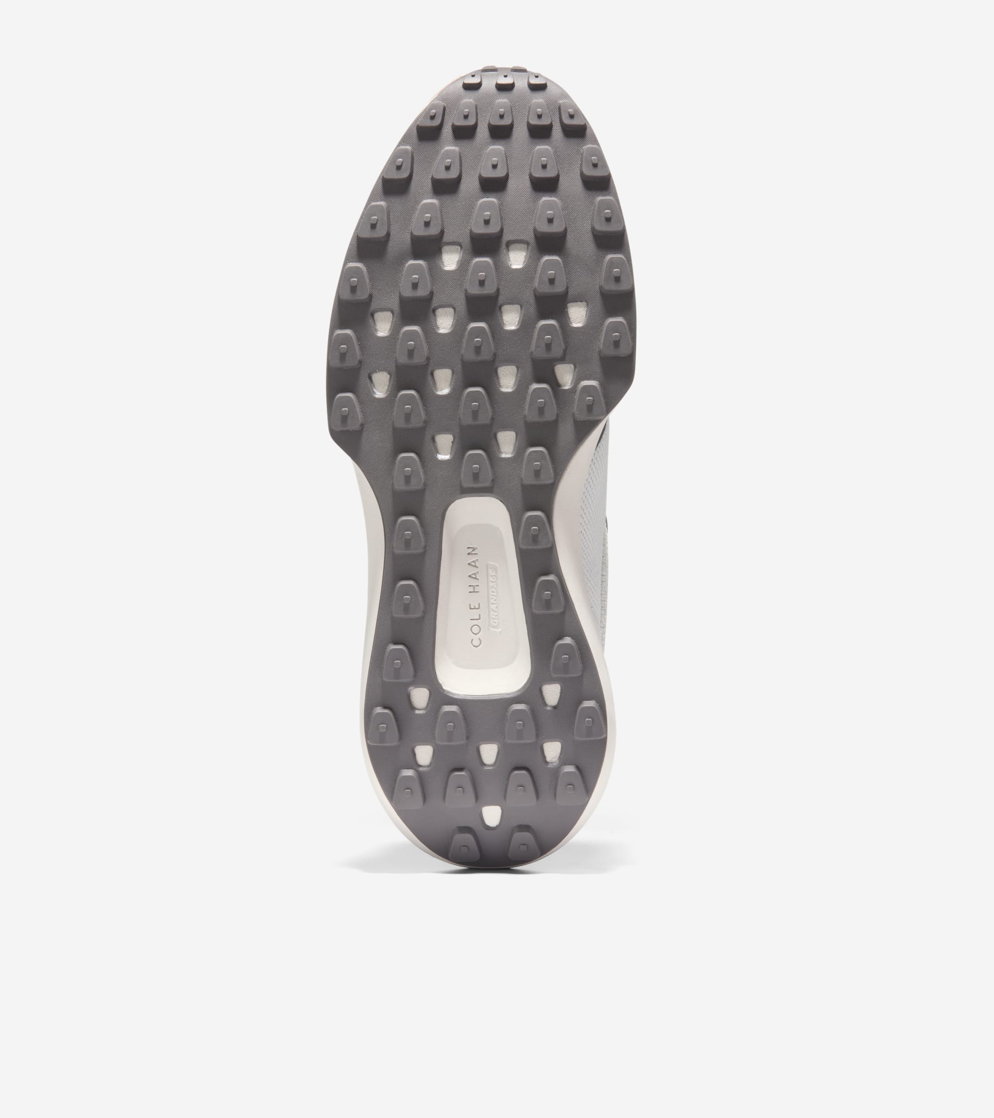 Bottom view of a sneaker sole with a dark gray textured outsole featuring many small nubs and a light gray midsole with Cole