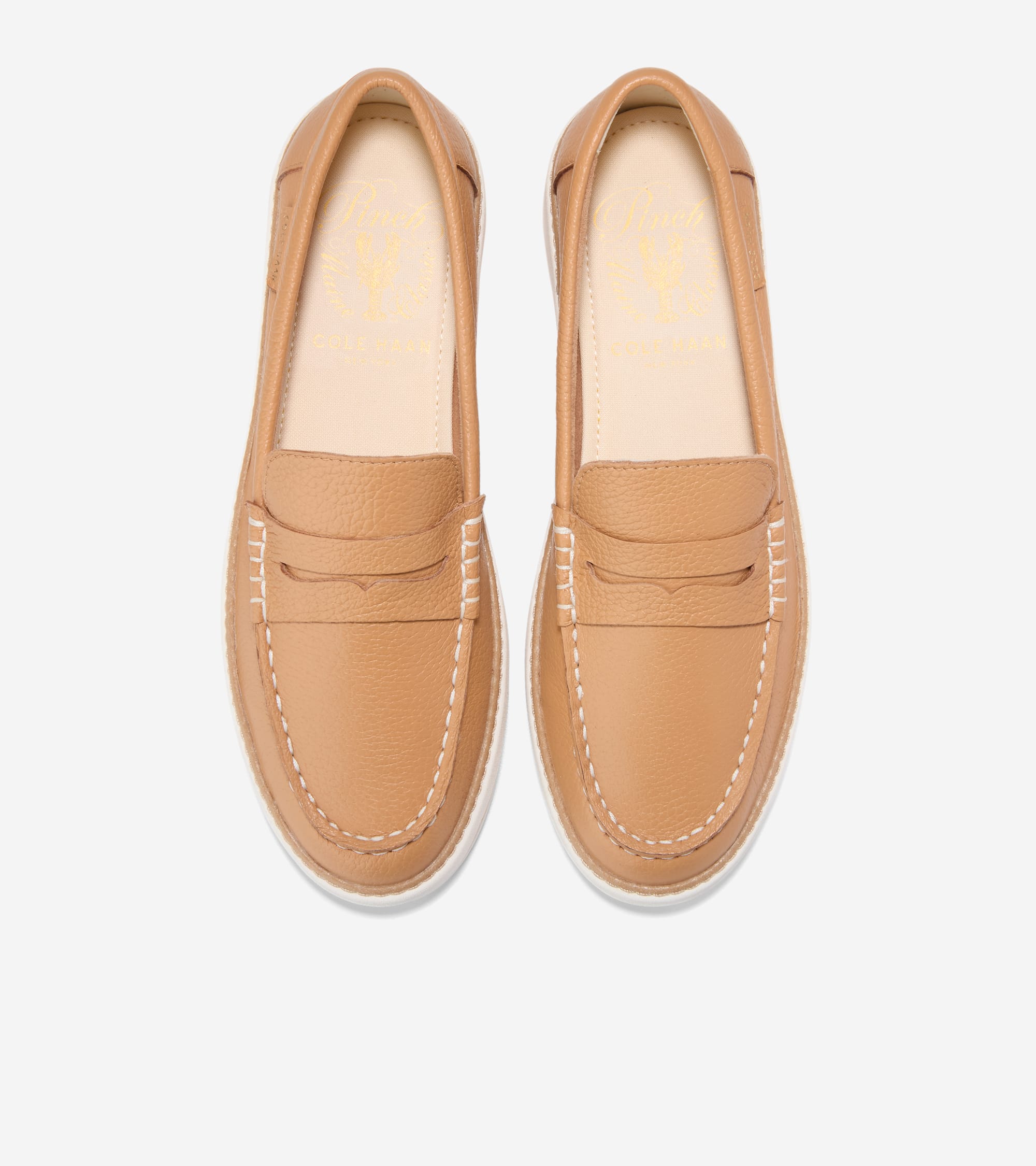 Pair of tan pebbled leather penny loafers with white stitching around the toe and sides, and white soles. Gold-toned branding