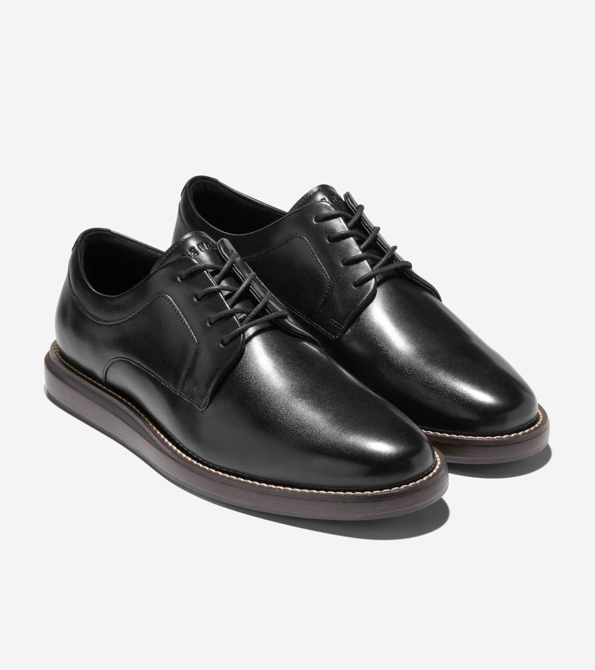 Pair of black leather plain toe Oxfords with black laces and thick dark brown soles featuring a light stitch detail.