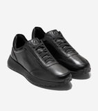 Pair of all-black leather slip-on sneakers with black laces, embossed Cole Haan logo on the side, and CH logo on the tongue.