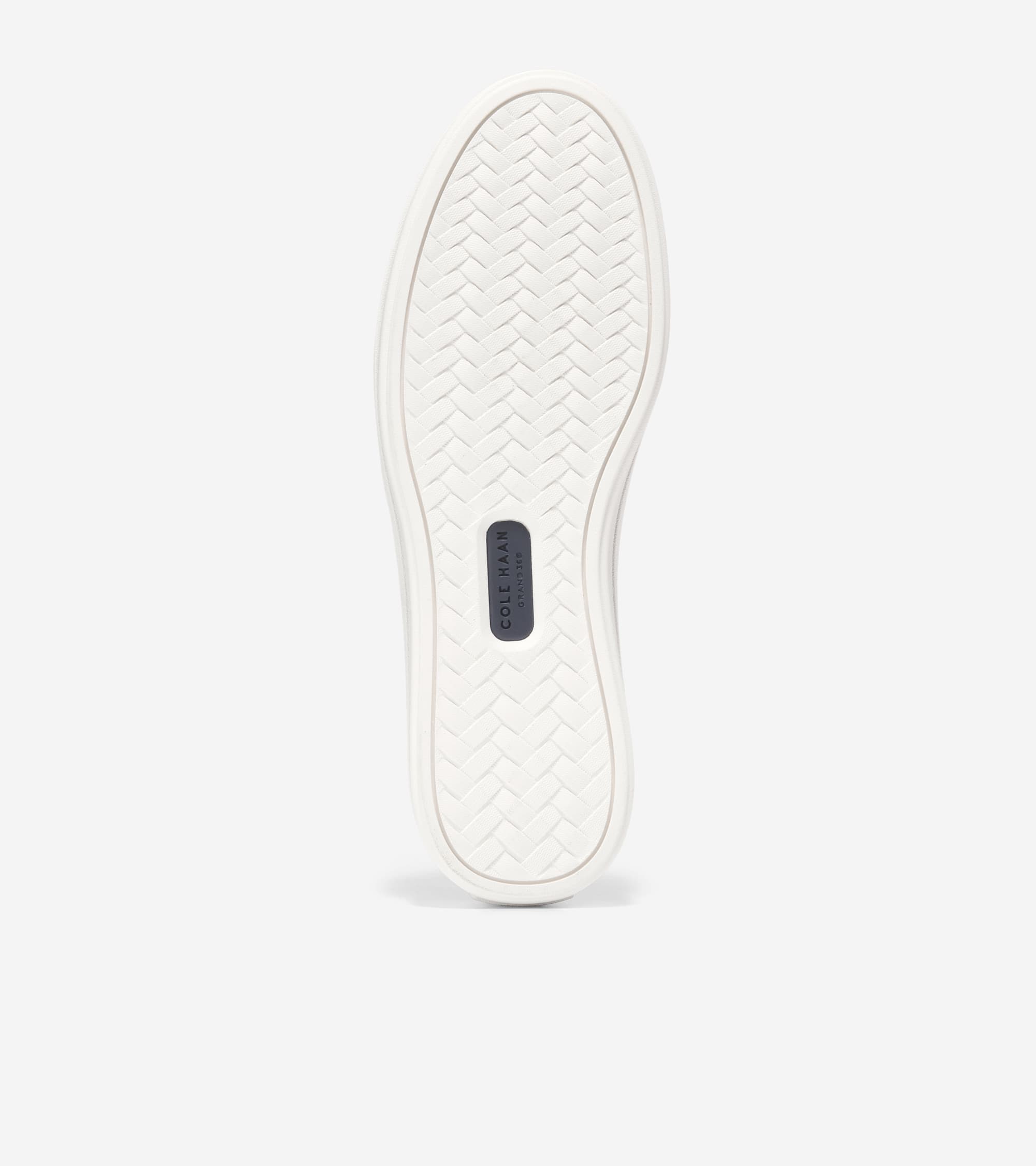 Underside of an off-white shoe sole with a textured herringbone pattern and a dark blue brand label near the heel.