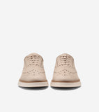 Pair of light beige leather wingtip oxfords with brogue perforations, matching laces, and thick cream soles.