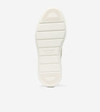 Off-white sneaker sole with horizontal grooves, D-shaped patterns at heel and toe, and 'COLE HAAN GRAND.ØS' branding.