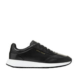 Black Cole Haan women's slip-on sneakers with white midsole, black outsole, and gold-toned branding on the side.