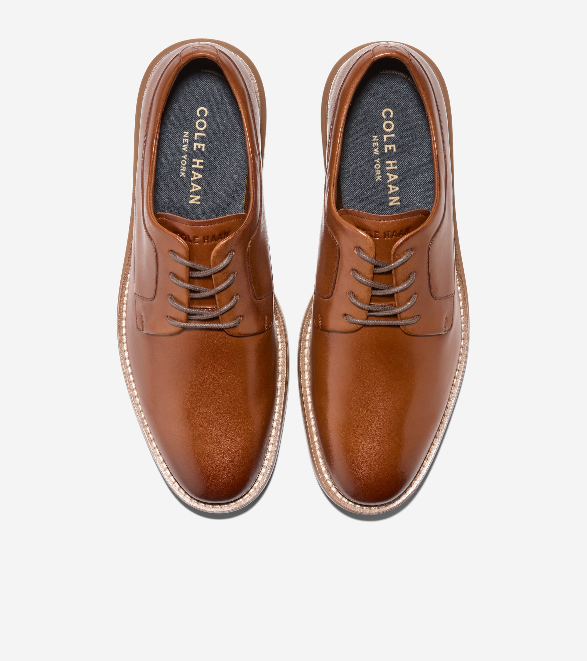 Pair of brown leather plain toe oxfords with grayish-brown laces, light brown soles, and white welt stitching.