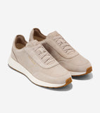 Light beige suede slip-on sneakers with elastic laces, white midsoles, and brown rubber outsoles. Gold-toned Cole Haan logo.
