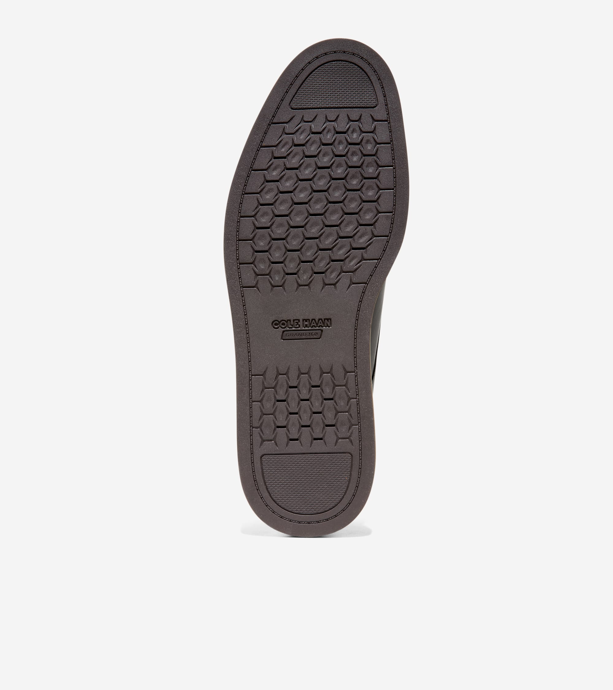 Dark brown shoe sole with a hexagonal traction pattern, smooth heel and toe sections, and "COLE HAAN GRAND.OS" branding.