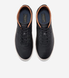 Pair of black leather low-top sneakers with black laces, tan collar trim, and white soles. Dark blue insoles show 'Cole Haan'