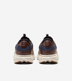 Pair of men's sneakers, back view. Dark blue knit upper with brown leather accents, "CH" logo on heel. Cream ribbed soles wit