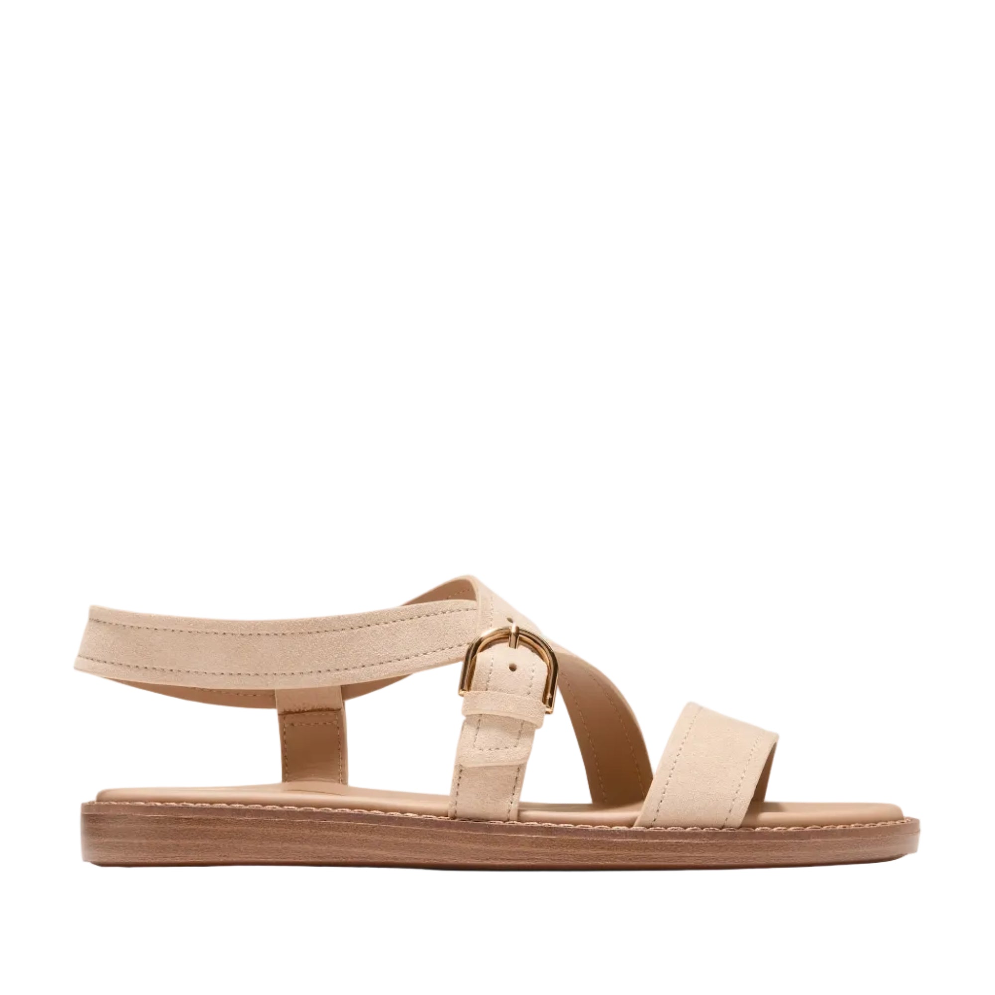 Light beige suede flat sandals with a wide toe strap, criss-cross mid-foot strap, and an ankle strap with a gold-toned buckle