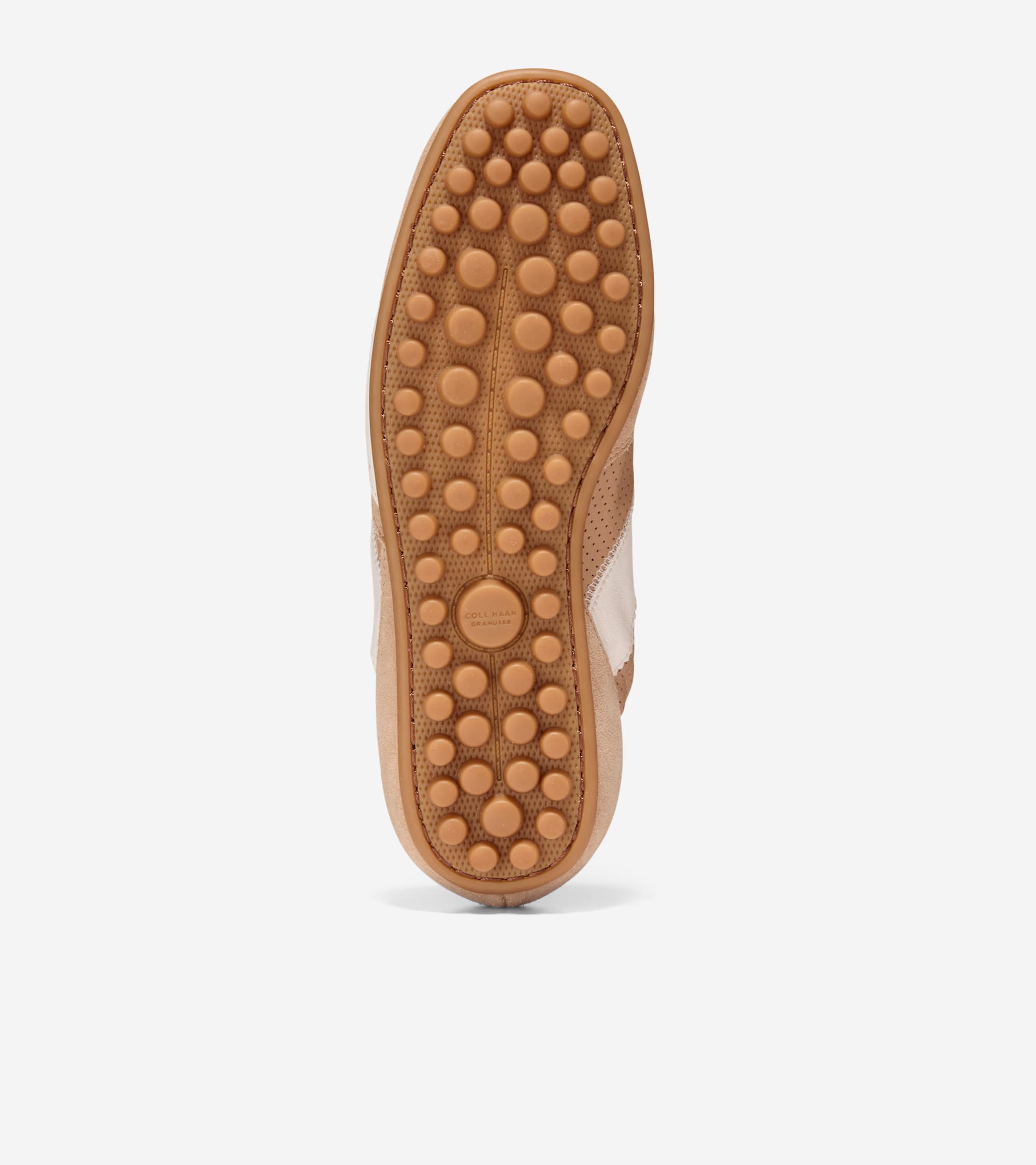 Single sneaker, bottom view. Tan rubber sole with circular nubs. Light brown perforated upper with white side stripe.