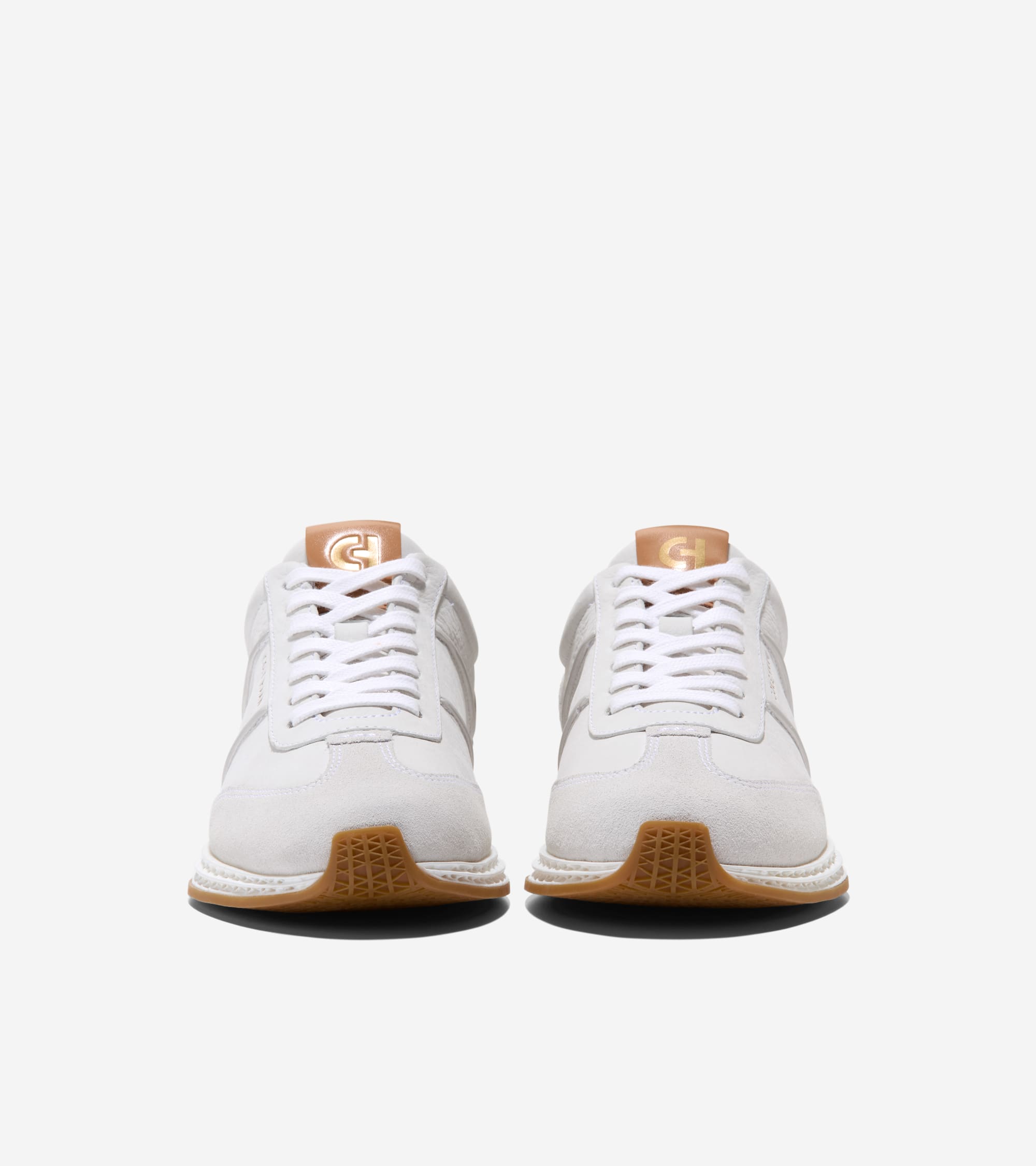 Pair of white low-profile sneakers with suede toe caps, white laces, tan tongue with gold-toned CH logo, and brown rubber out