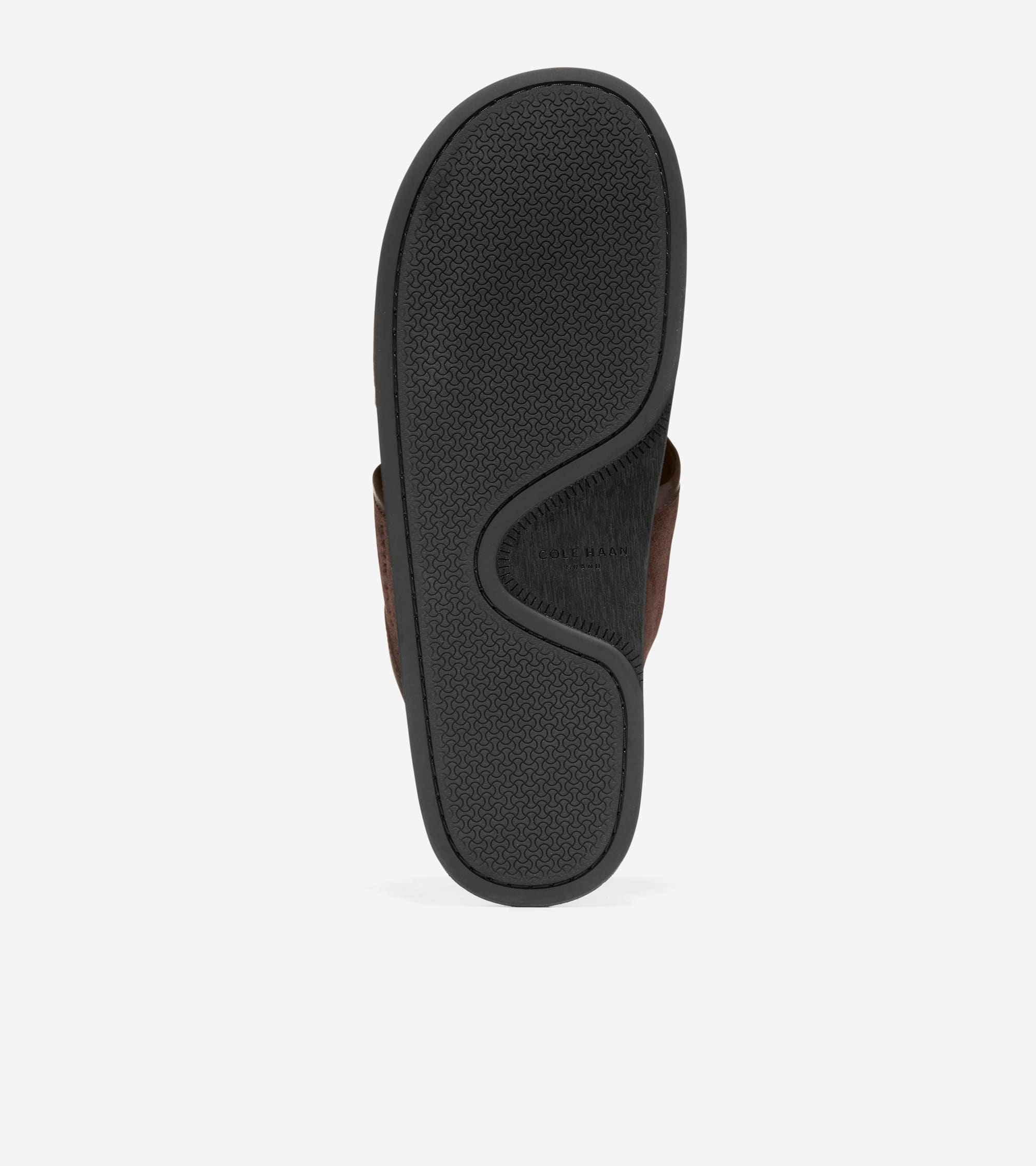 Bottom view of a brown sandal with a dark gray rubber sole. The sole has a textured pattern and a curved indentation with 'CO