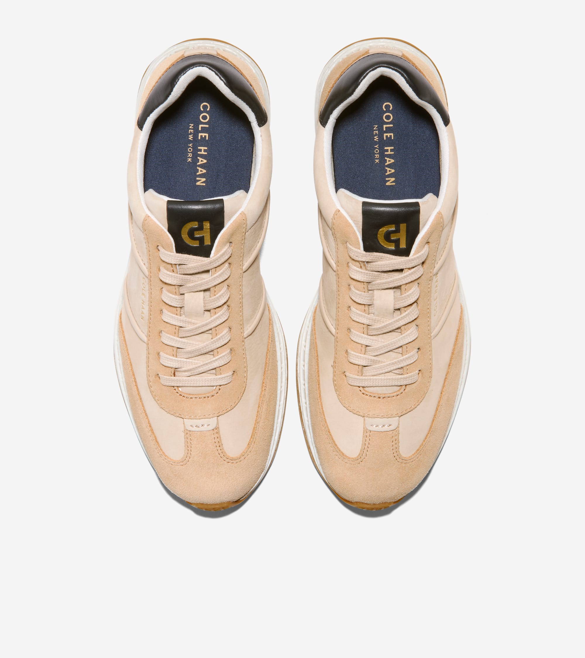 Light beige sneakers with white soles, brown outsoles, black heel trim and tongue tags with gold-toned 'CH' logos.